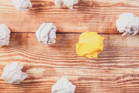Set of crumpled paper balls and one yellow on wooden backgroundの写真素材