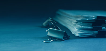 Close up of a pile of documents and binder clips on blue backgroundの写真素材