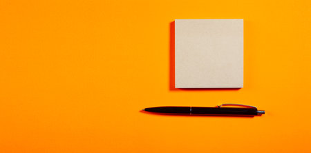 Blank notepad with pen on orange background. Copy space.の写真素材