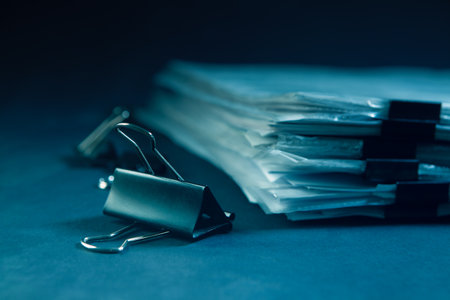 Pile of documents and binder clips on dark blue background.の写真素材