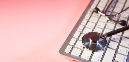 Stethoscope on a computer keyboard with pink background, medical conceptの写真素材