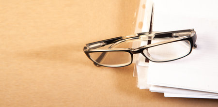 Glasses on a stack of papers on a wooden background. Business conceptの写真素材