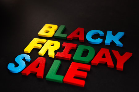 Black Friday sale text in colorful wooden letters on a black background.の写真素材