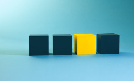 Three black and yellow cubes standing in a row on a blue backgroundの写真素材