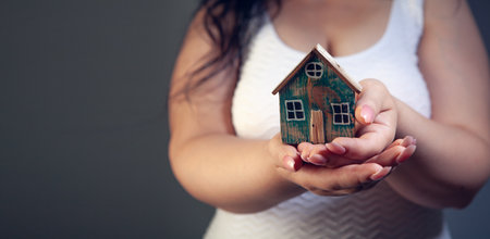 Woman holding a model of a house in her hands on a gray backgroundの写真素材