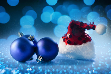 Christmas background with santa hat and blue balls on bokeh backgroundの写真素材