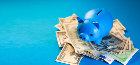 Piggy bank and money on a blue background with copy spaceの写真素材
