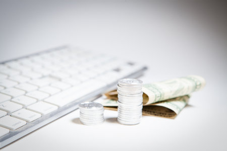 Coins on the keyboard with a dollar bill on a white background