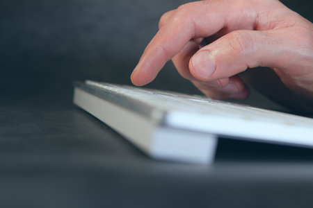 Man's hand holding a book on a dark background. Close up