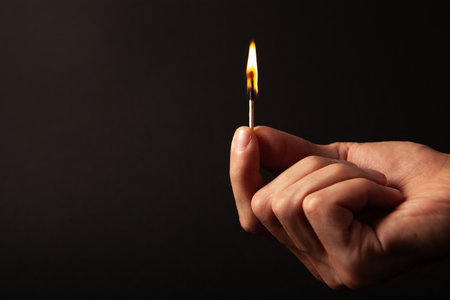 Burning match in hand on dark background, closeup. Space for textの写真素材