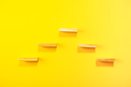 Top view of wooden dominoes on yellow background. Business concept