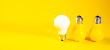 Light bulb and incandescent bulbs on yellow background with copy space