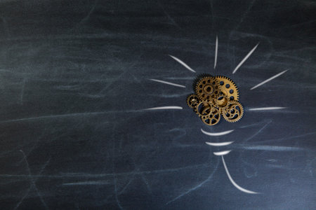 Idea concept with light bulb and gear mechanism on chalkboard background