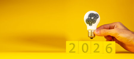 Light bulb in hand on yellow background. New Year 2016 concept.