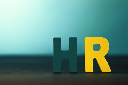 Wooden letters spelling the word HR on a dark background, business concept