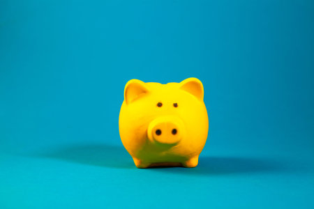 Yellow piggy bank on blue background, saving money for the futureの写真素材