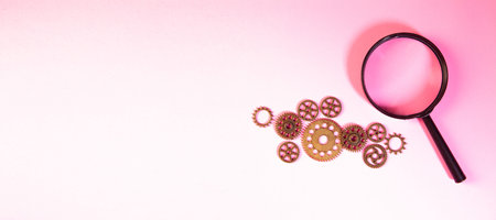 Magnifying glass and gears on pink background. Minimalism concept.の写真素材