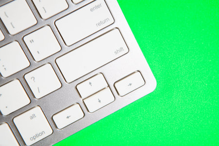 Close up of a modern white computer keyboard on a green background.の写真素材