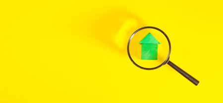 house magnifying glass with the house on yellow background. real estate concept.の写真素材