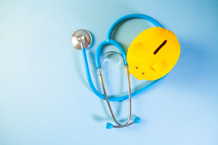 Blue piggy bank and stethoscope on blue background. Health care concept.の写真素材