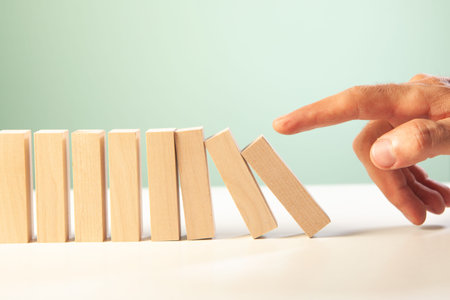 hand of businessman putting wooden domino effectの写真素材