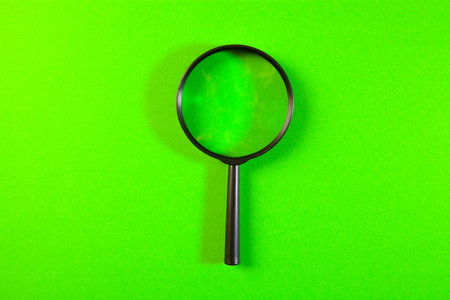 Magnifying glass on a green background. View from the top.の写真素材