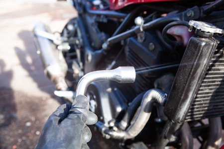 Close-up of hand of mechanic changing oil on motorcycle engine.