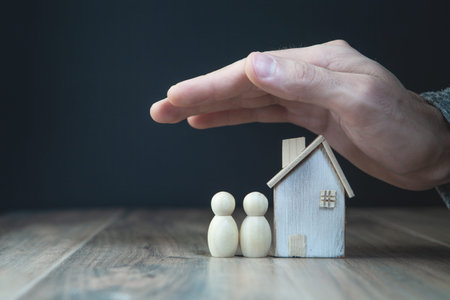 Real estate concept. Hand of real estate agent holding wooden house model.