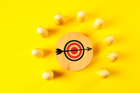 Wooden target with arrow on a yellow background.