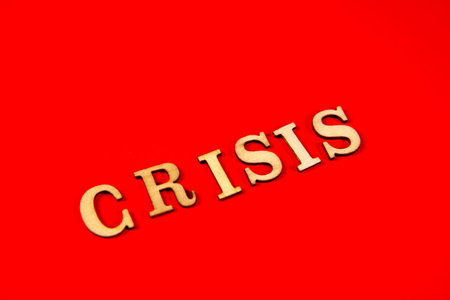 Wooden letters in the form of the word crisis on a red background