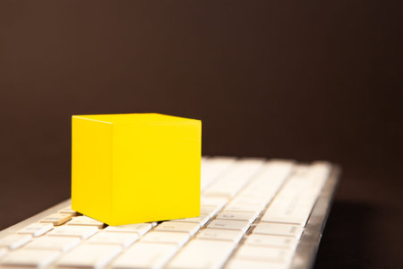 Yellow cube on a computer keyboard on a dark background, business concept