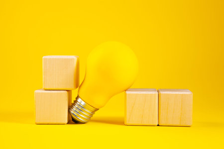Yellow light bulb and wooden cubes on a yellow background. Business concept