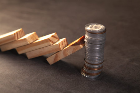 Stack of coins and wooden dominoes on dark background. Business concept.の写真素材