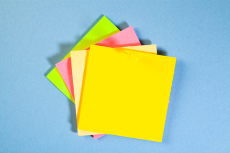 Colored sticky notes isolated on blue background with space for text.