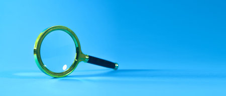 Magnifying glass on blue background, shallow depth of field (DOF)の写真素材