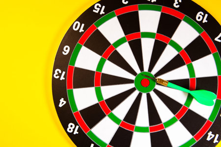 Dart board with dart arrow on yellow background, business success concept