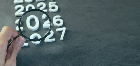Magnifying glass and numbers 2026 2027 on blackboard background with copy spaceの写真素材