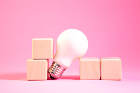 Light bulb and wooden cubes on a pink background. Business concept.の写真素材