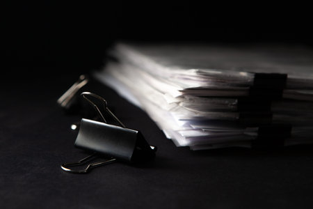 Close up of a pile of documents with a black paperclip.