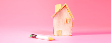 wooden house with a pink toy on a pink background. real estate conceptの写真素材