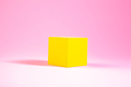 yellow cube in the shape of a cube on a pink background.