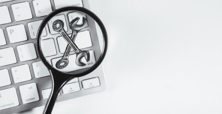 Magnifying glass and keyboard on white background. View from above.