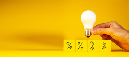 Light bulb with percentage sign on yellow background with copy space for text.