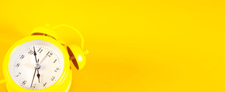 Yellow alarm clock on yellow background with copy space. Time concept.