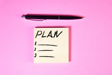 Plan written on a sticky note with a pen on a pink background