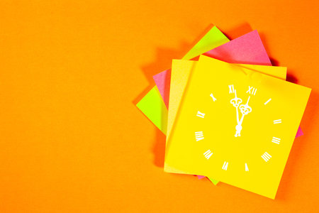 Clock and colorful sticky notes on orange background. Time management concept.