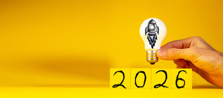 New Year concept with lightbulb in hand on yellow background.