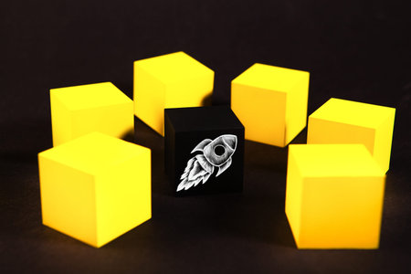 Rocket on black cube and yellow cubes on black background, start up concept