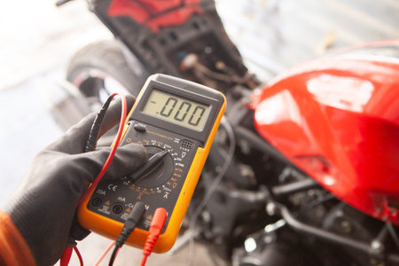 mechanic with multimeter and red motorcycle in the garage.