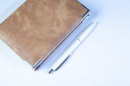 Notebook and ballpoint pen on white background with copy space.